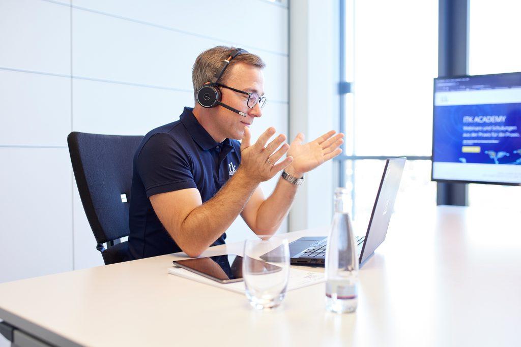 ITK Mitarbeiter im Gespräch mit Headset am Laptop