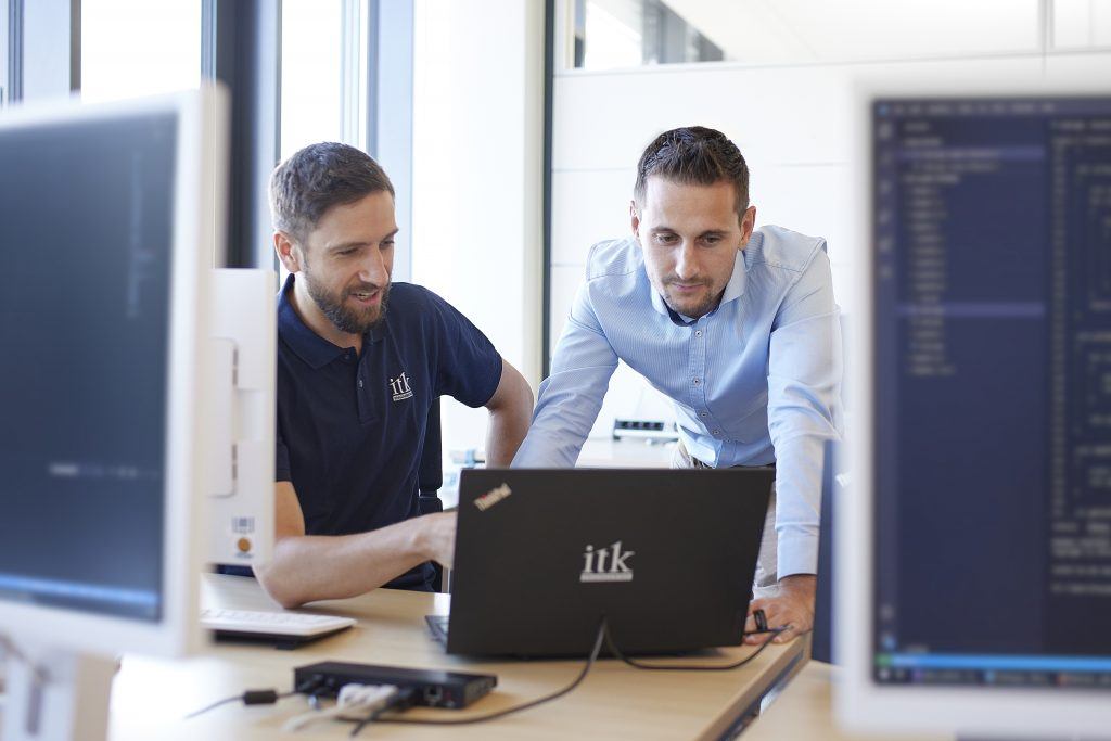 Two employees of ITK are looking at a laptop and analyzing processes