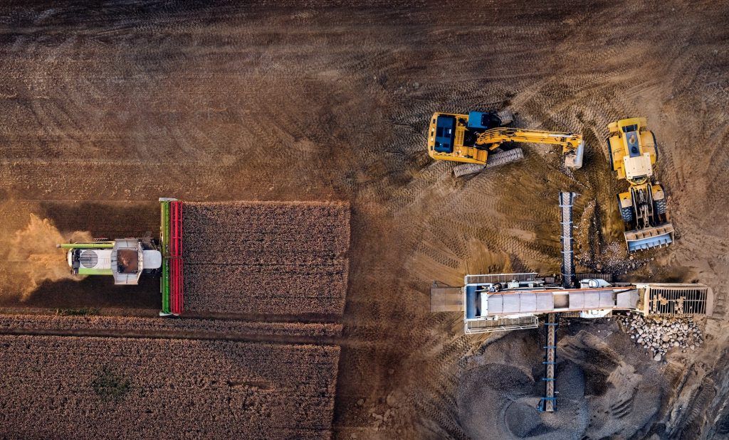 Traktor auf dem Feld und Bagger auf einer Baustelle