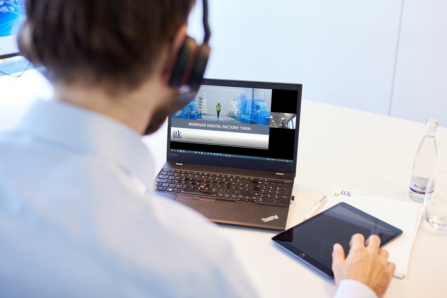Blick über die Schulter auf einen Laptop mit Webinar-Folien 