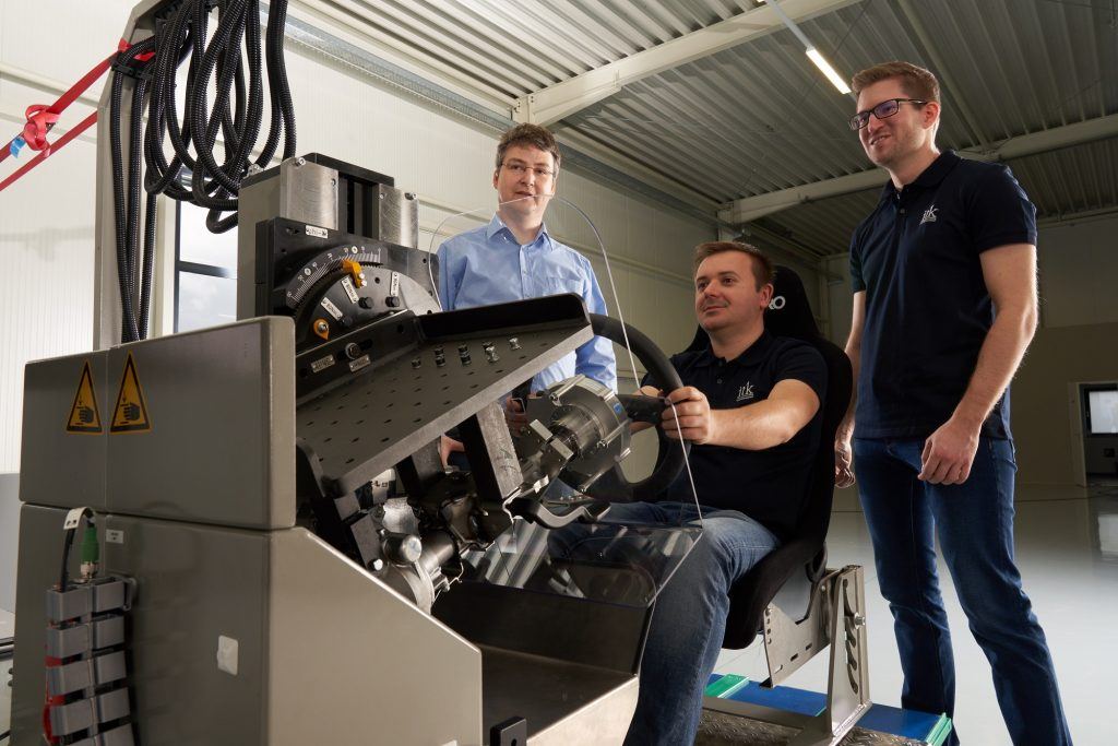 Three engineers testing at a steering test bench
