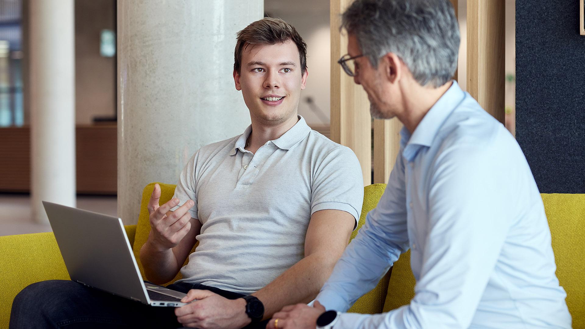 2 ITK Mitarbeiter sitzen im Gespräch vor einem Laptop.