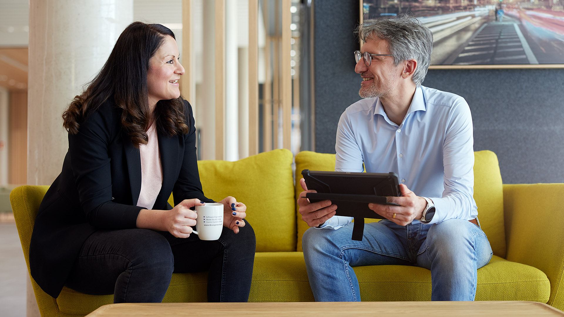 2 ITK Mitarbeiter:innen tauschen sich auf einem Sofa im Büro aus.