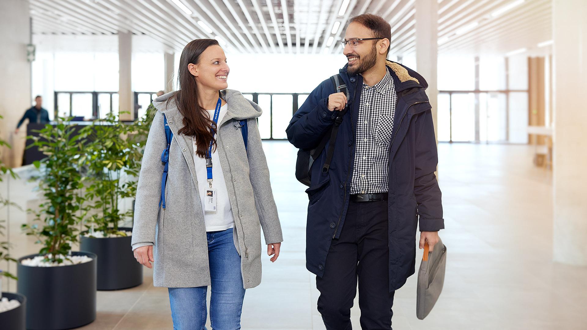 Zwei ITK Mitarbeiter, die sich unterhaltend durch das Büro laufen 
