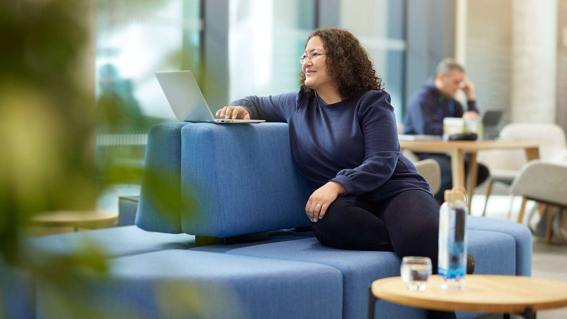 An ITK employee sitting on a blue sofa in the open space of the office.