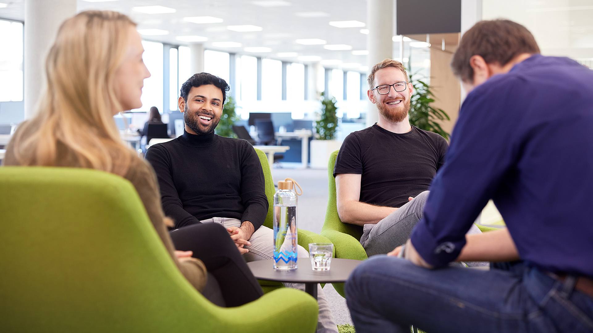 Vier ITK Mitarbeiter, die sich im Open Space des Büros unterhalten.