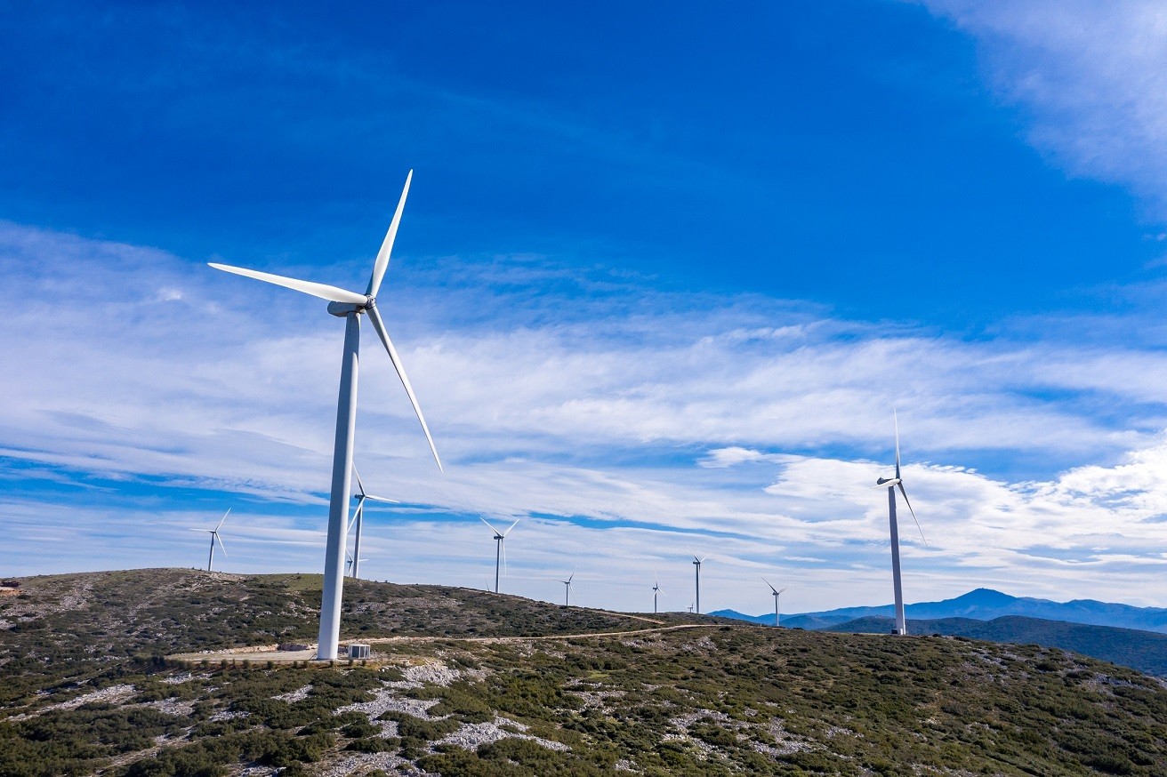 Wind turbines on the hill, Wind farm, aerial drone view. Green ecological power energy generation. Alternative energy plant, blue cloudy sky, Greece