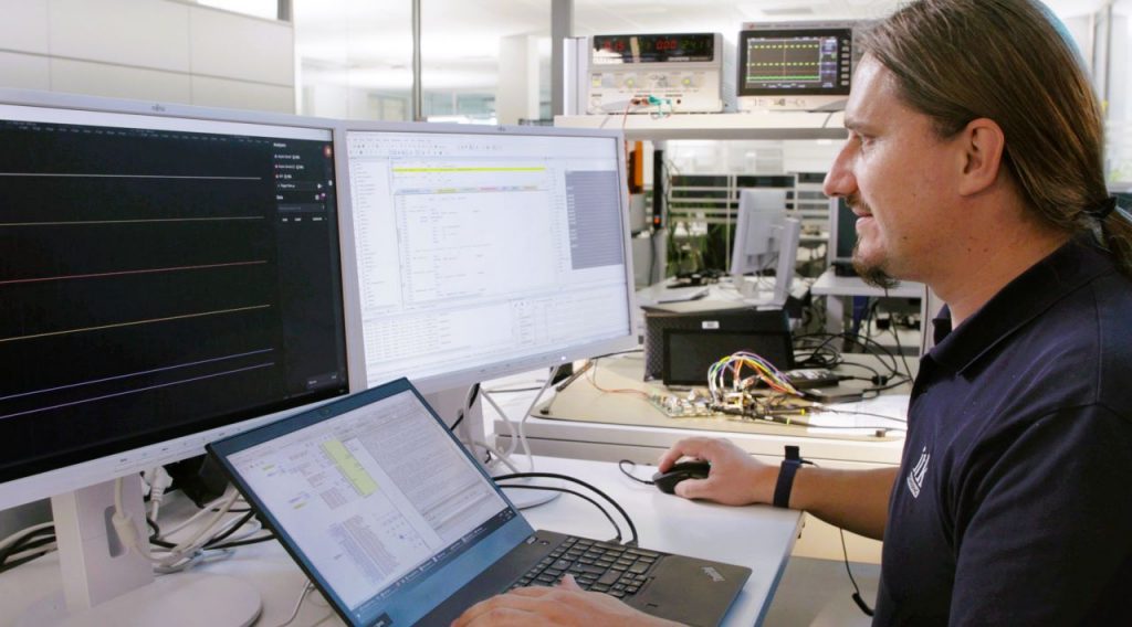 An engineer develops software and works on a laptop with two screens.