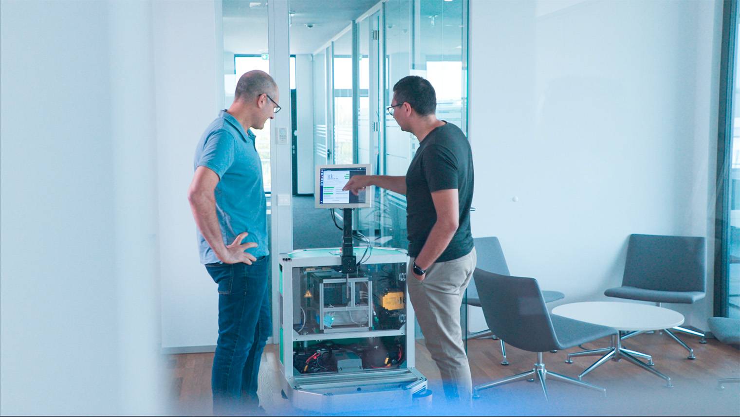 Zwei Ingenieure stehen an einem mobilen Roboter und diskutieren die Benutzeroberfläche.