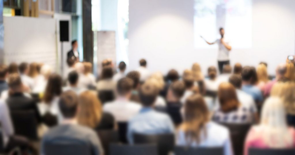 Vortrag eines Speakers vor sitzendem Publikum.