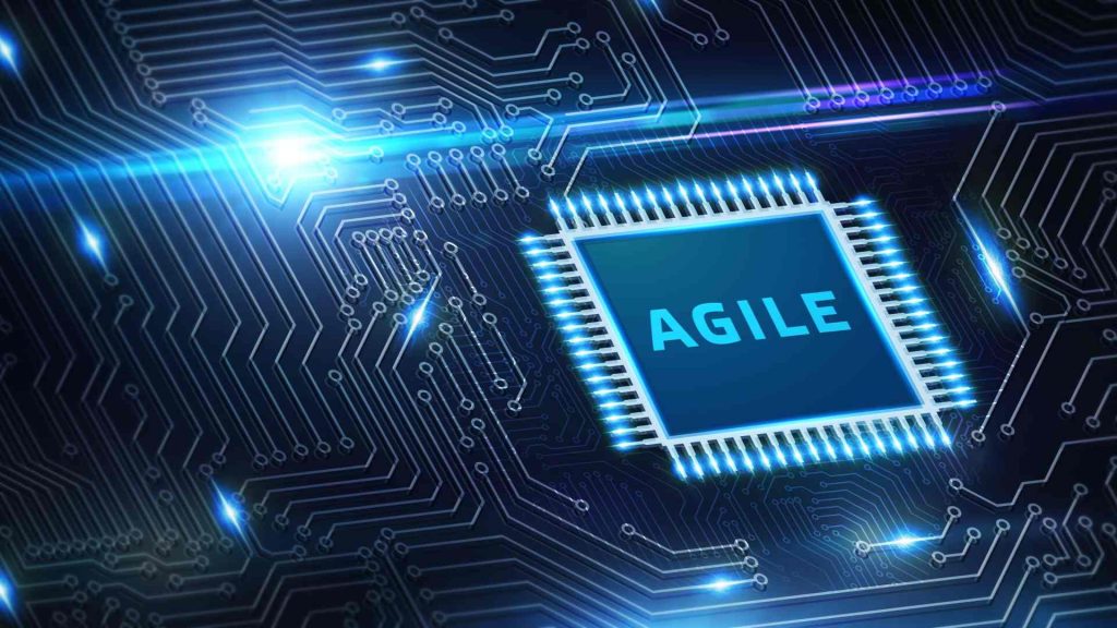 The word “Agile” in blue lettering on a circuit board against a dark background symbolizes agile software development.