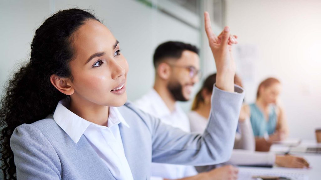 A woman raises her hand to ask a question.
